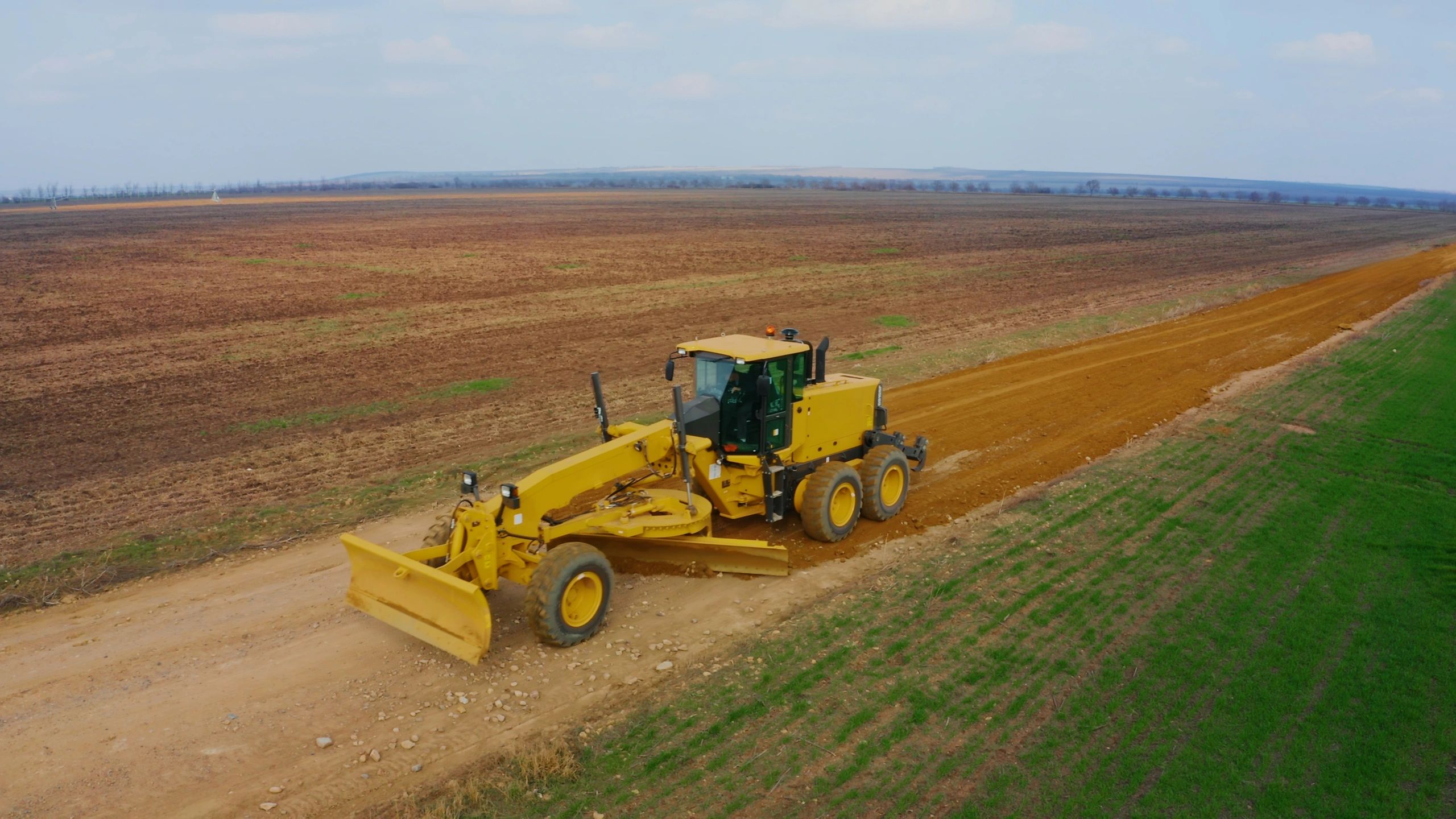 Road grader leveling a dirt road for infrastructure works